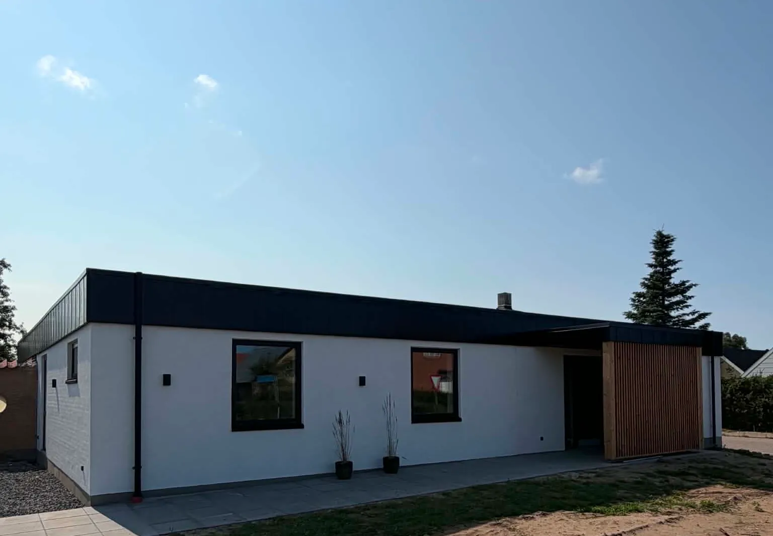 Moderne hvid villa med sort tagkant og listeparti ombygget af Brix Byg